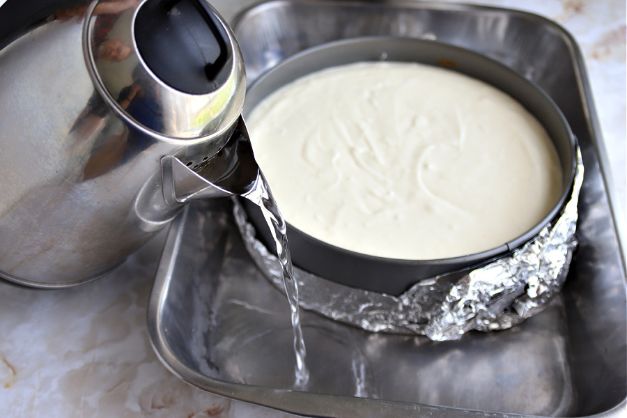 Pouring water bath for triple lemon curd cheesecake dessert. 