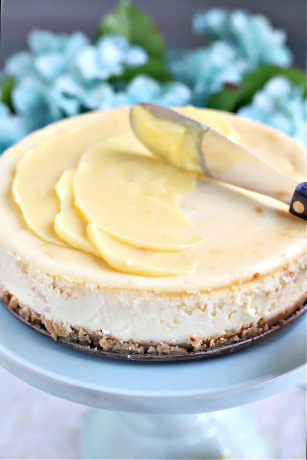 Spreading homemade lemon curd topping to baked Philadelphia cream cheese cheesecake.