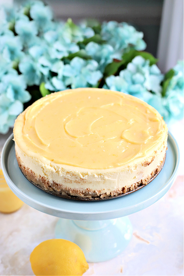 Spreading homemade lemon curd topping to baked Philadelphia cream cheese cheesecake.