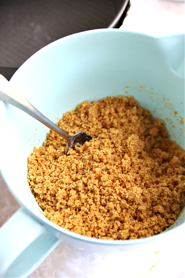 Preparing graham cracker crumb crust for triple lemon cheesecake.