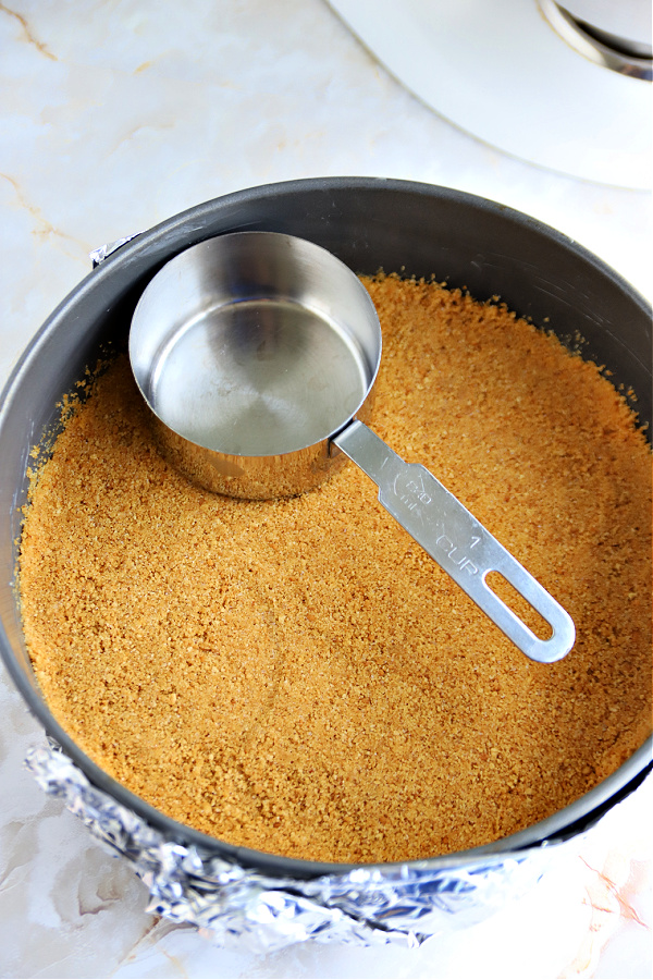 Preparing graham cracker crumb crust for triple lemon cheesecake.