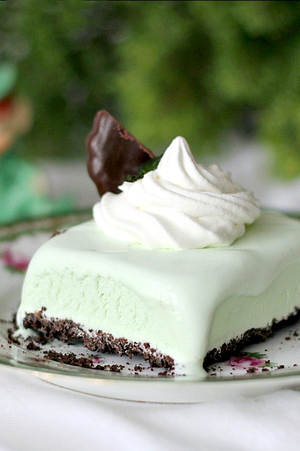 Frozen, minty Grasshopper Dessert Squares are the perfect St Patrick's day treat or any time you want an easy, no-bake dessert. Crust is made using fudge mint cookies and then filed with ice cream and topped with a dollop of whipped cream. Make ahead and freeze and it is ready whenever you want.