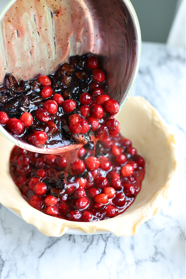 adding the filling to the pie crust for cranberry and fig pie