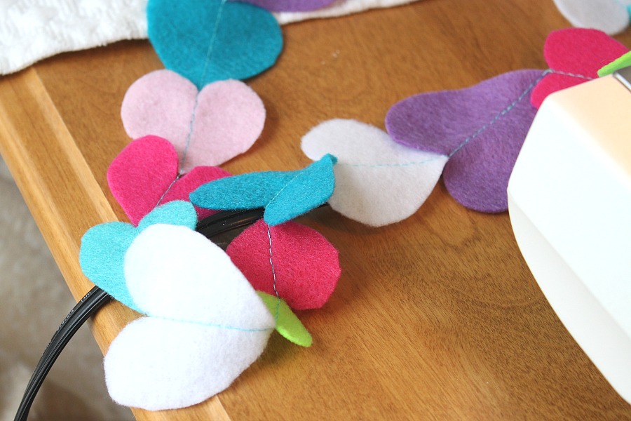 Easy Valentine's Day garland made by sewing felt hearts together. Hang hearts overflowing garland on the mantle, a window or wherever happy hearts are wanted.