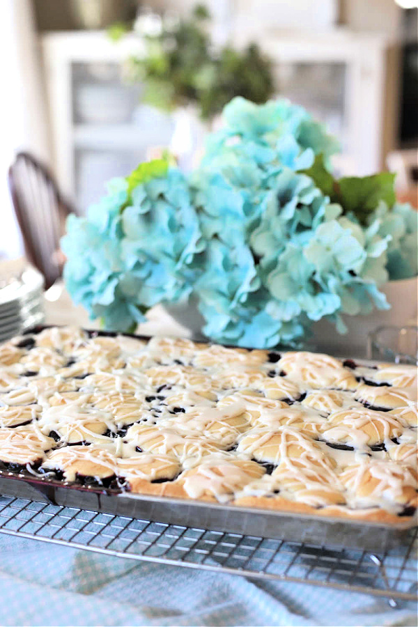 Drizzling frosting glaze onto cherry blueberry fruit bars.