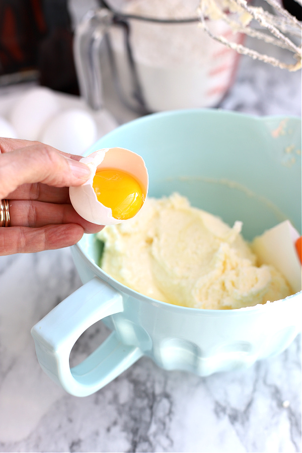 Adding eggs and ingredients to make cherry blueberry fruit bars.