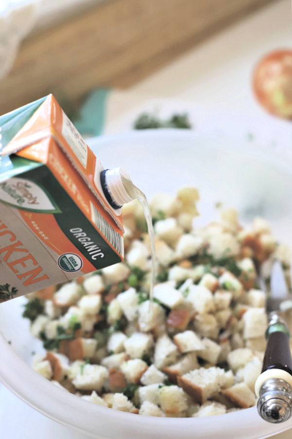 adding chicken broth to bread cubes