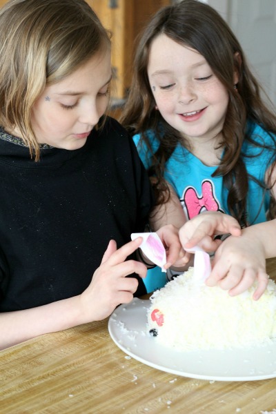 This adorable Easter bunny cake is made using a box cake and frosting (either homemade or from a tub). Our girls had the best time assembling it and were overjoyed with their finished creation. Truly a fun project and a lovely Easter dessert. It looks super cute on the holiday table.