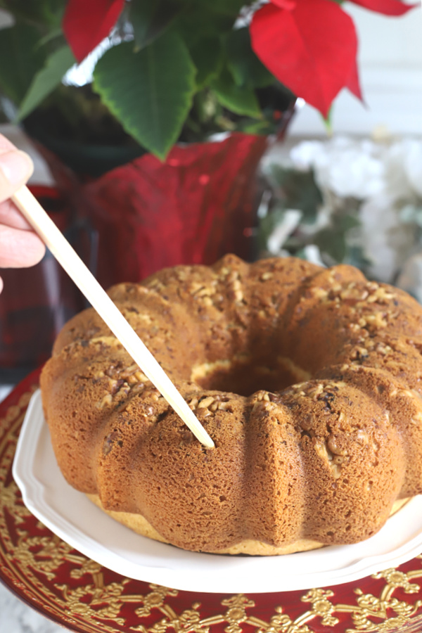 Poking holes on the baked rum cake before drizzling on the rum glaze.