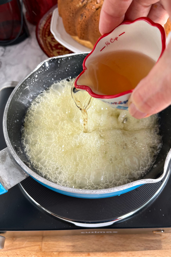 Adding the rum to the melted butter to top the baked rum cake.