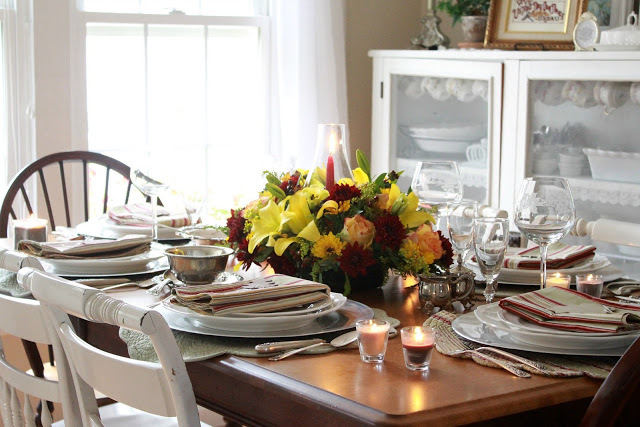 Flowers add a festive touch to your Thanksgiving table. Lovely autumn colors with a hurricane globe & candles creates an elegant tablescape. 