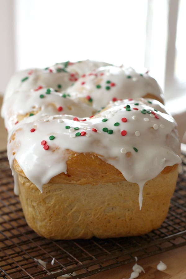 Bake a festive loaf of rich holiday brioche from easy recipe using a bread machine. Frosted with a white glaze and colorful sprinkles. Great food gift idea.