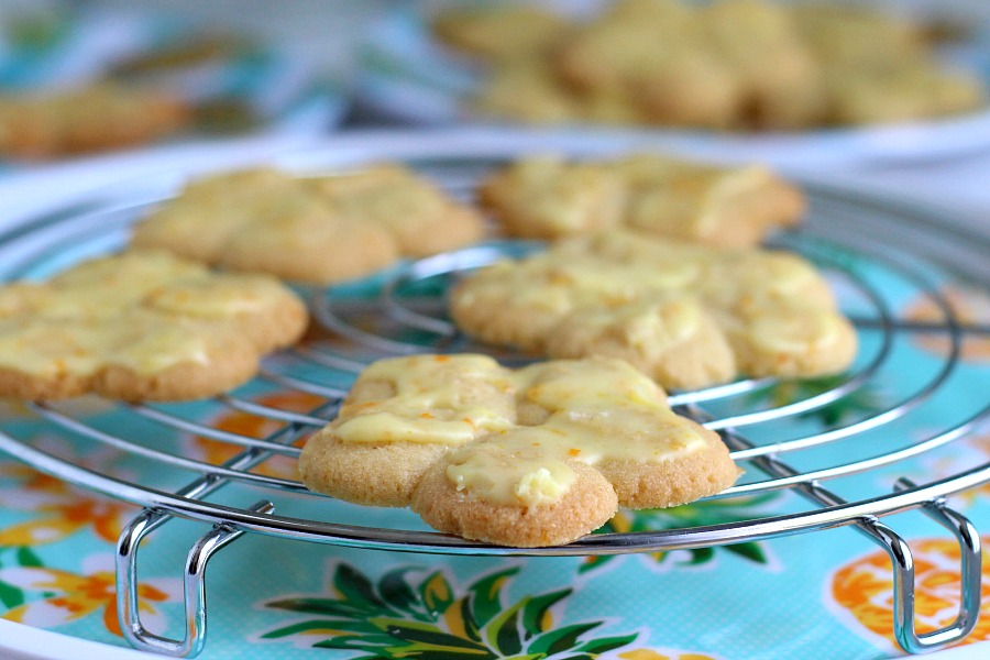 Frosted orange crisps are cookies flavored with orange in the dough and topped with a light orange frosting. They are crisp, tender and the citrus provides a nice surprise in each bite. Made using a cookie press similar to spritz or shortbread cookies but are sweeter. Perfect with a cup of tea, coffee or glass of milk.