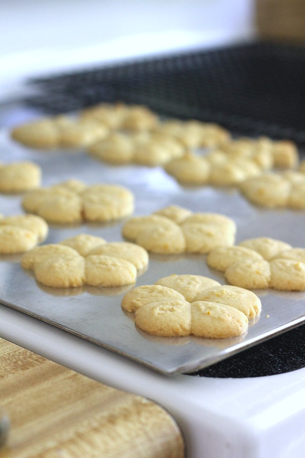 Frosted orange crisps are cookies flavored with orange in the dough and topped with a light orange frosting. They are crisp, tender and the citrus provides a nice surprise in each bite. Made using a cookie press similar to spritz or shortbread cookies but are sweeter. Perfect with a cup of tea, coffee or glass of milk.