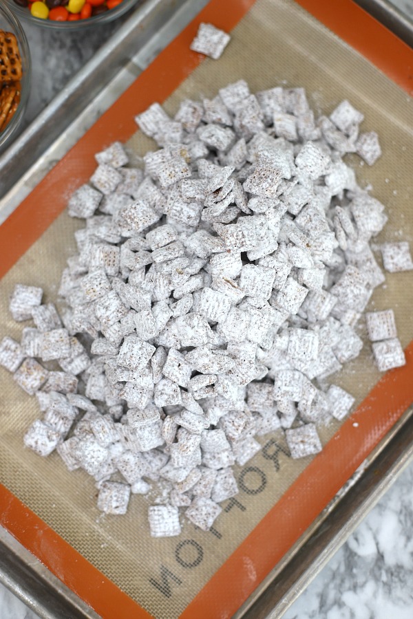 Easy to make, autumn puppy chow is a kid and adult favorite Halloween party snack. Chex mix, chocolate, peanut butter and candy corn tossed with confectioners sugar is a frightfully delicious concoction!