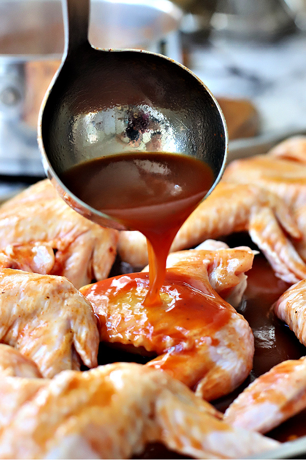 Basting sticky chicken wings with orange glaze