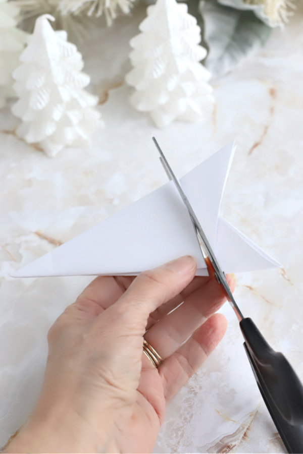 cutting the folded paper for making paper snowflakes