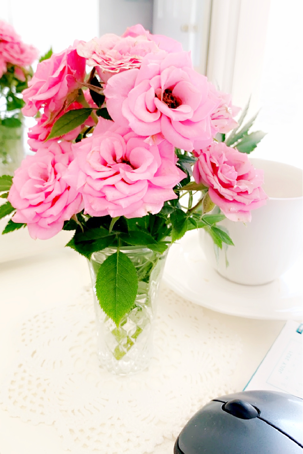 Pink miniature roses gathered after the rain, brighten an office desktop 