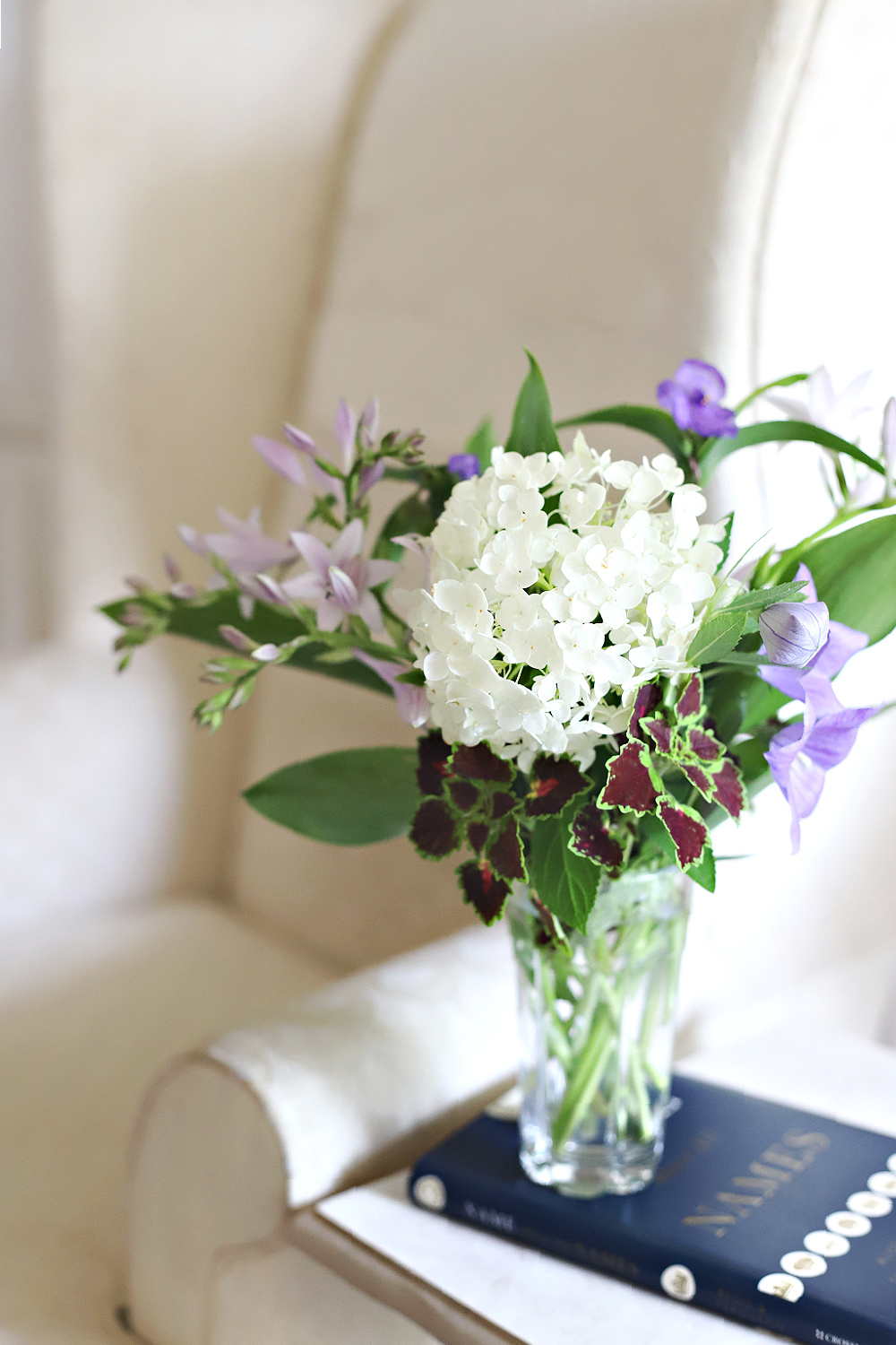 Snippets of flowers gathered after the rain arranged in a vase by the reading chair.