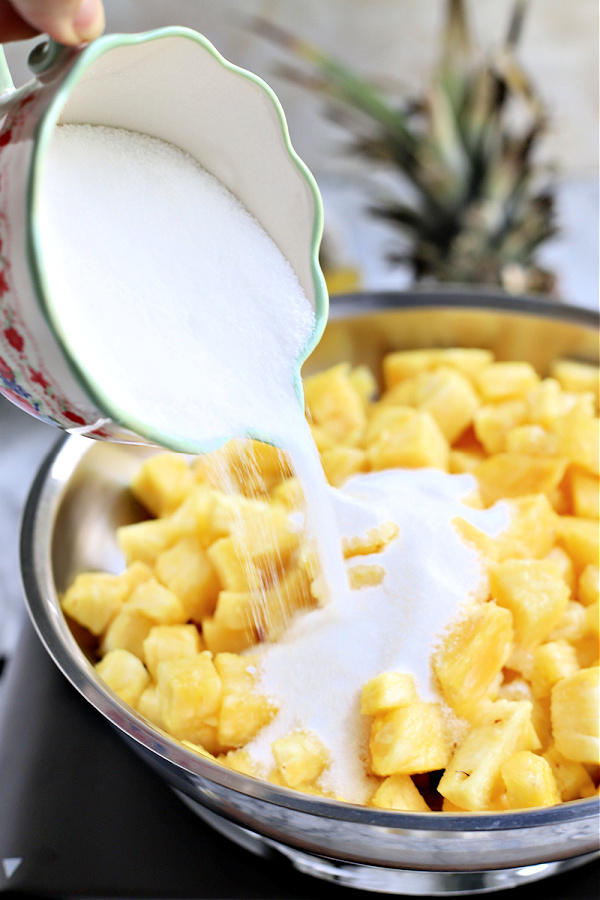 Adding sugar to fresh pineapple for jam