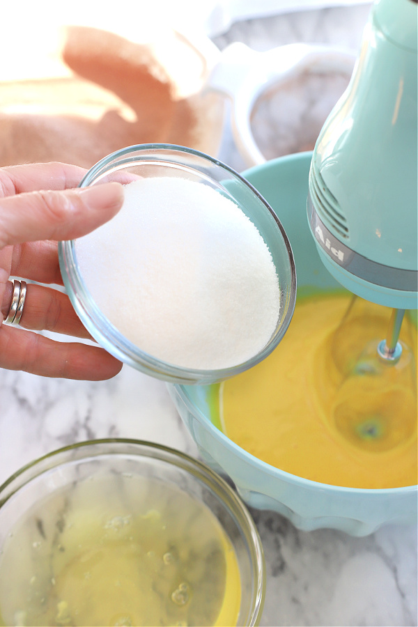 Adding the sugar to egg yolks for mocha yule log dessert.