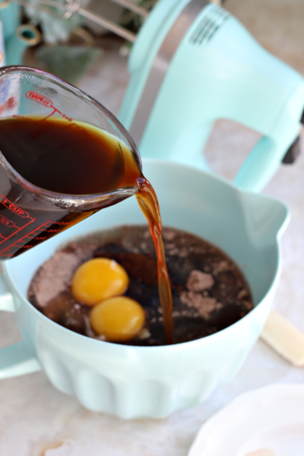 Adding cooled strong coffee to the chocolate mocha cake batter.