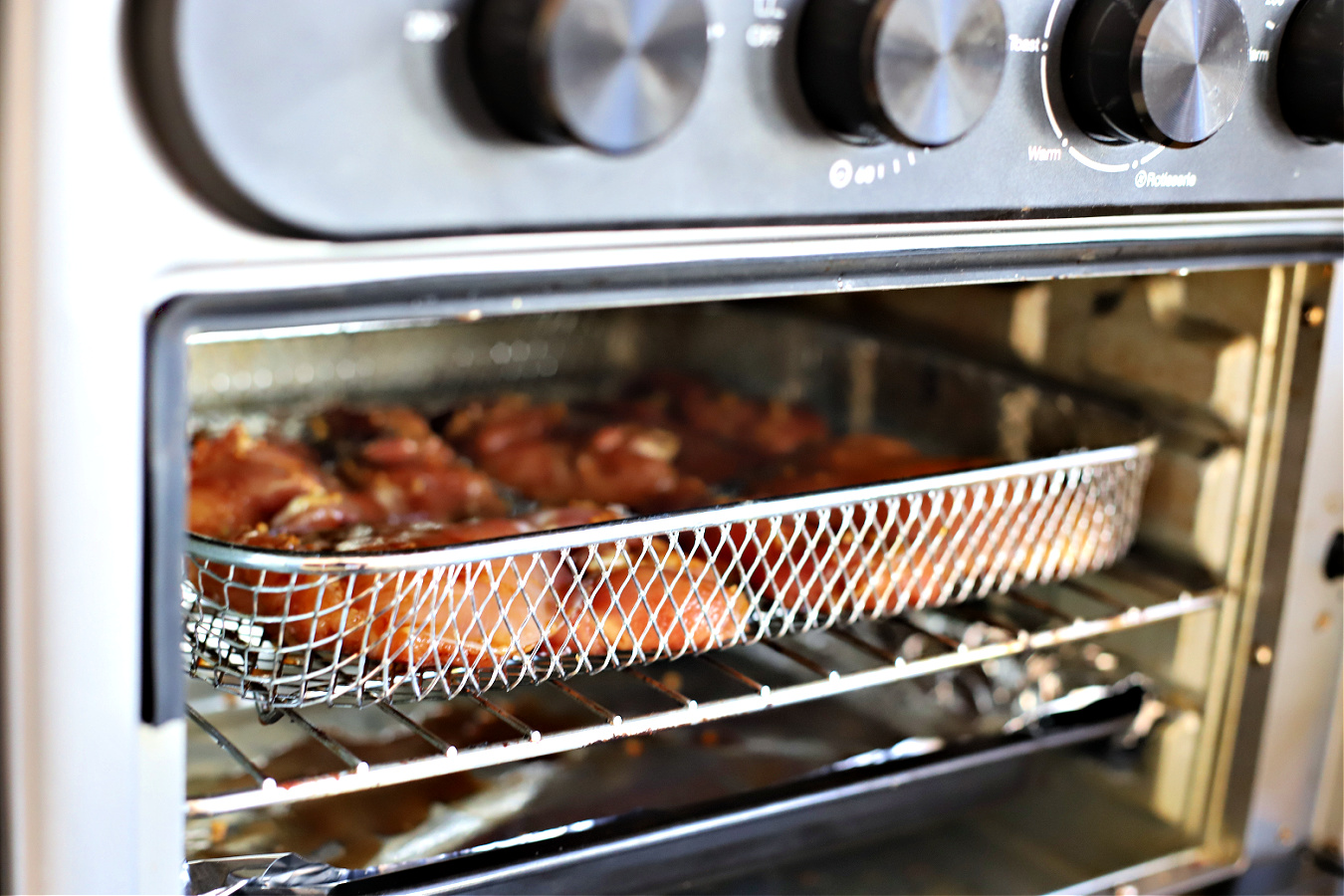 Skinless, boneless chicken thighs cooking in the air fryer.