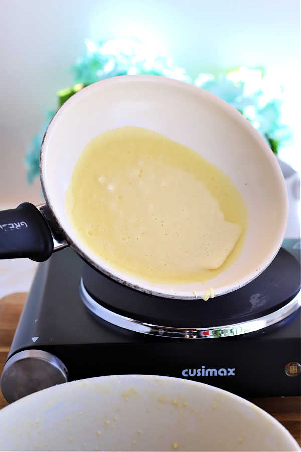 Tilting the pan with the batter for homemade manicotti crepes.