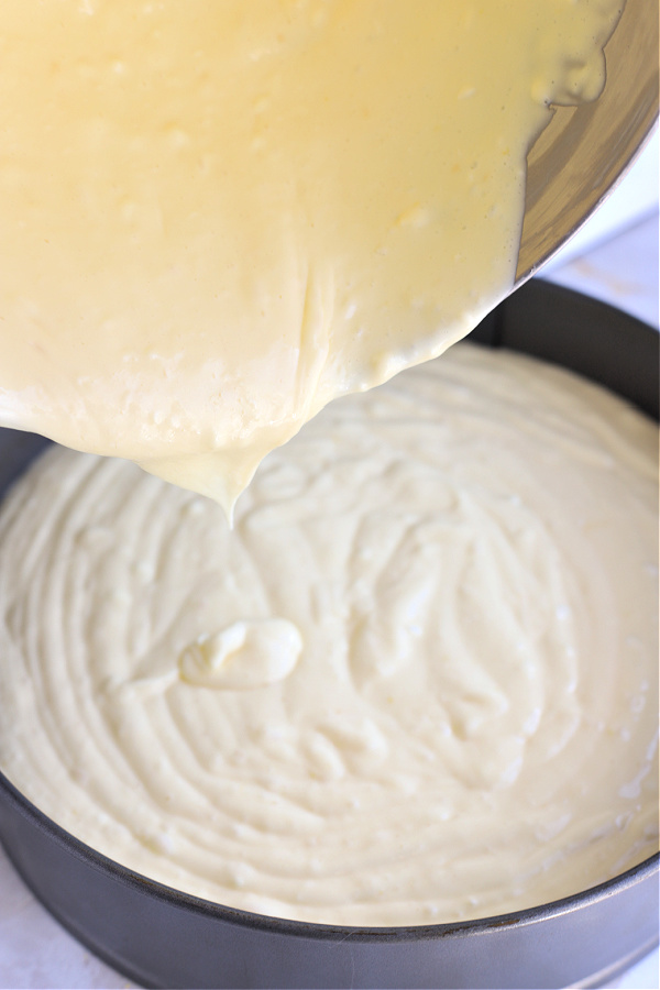 Pouring the cream cheese batter into prepared springform pan for NY style cheesecake recipe.