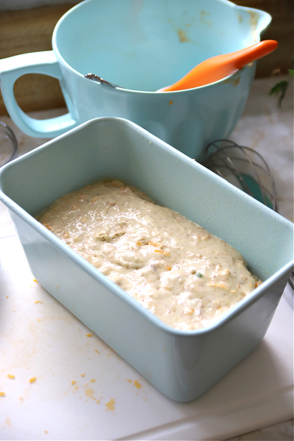 Adding the cheddar cheese bacon and wheat germ recipe mixture to prepared loaf pan for baking.