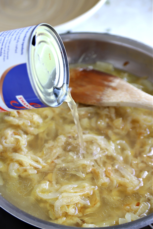 Adding chicken stock to caramelized onions for gravy for British bangers and mash recipe.