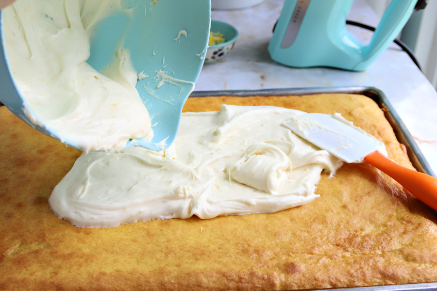 Spreading cream cheese frosting on cooled lemon sheet cake.