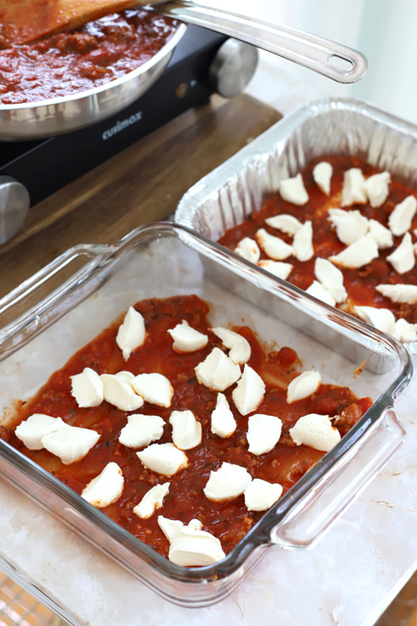 Beginning to layer the sauce, browned Italian sausage, mozzarella, ricotta, Parmesan and pasta for baked ziti casserole.