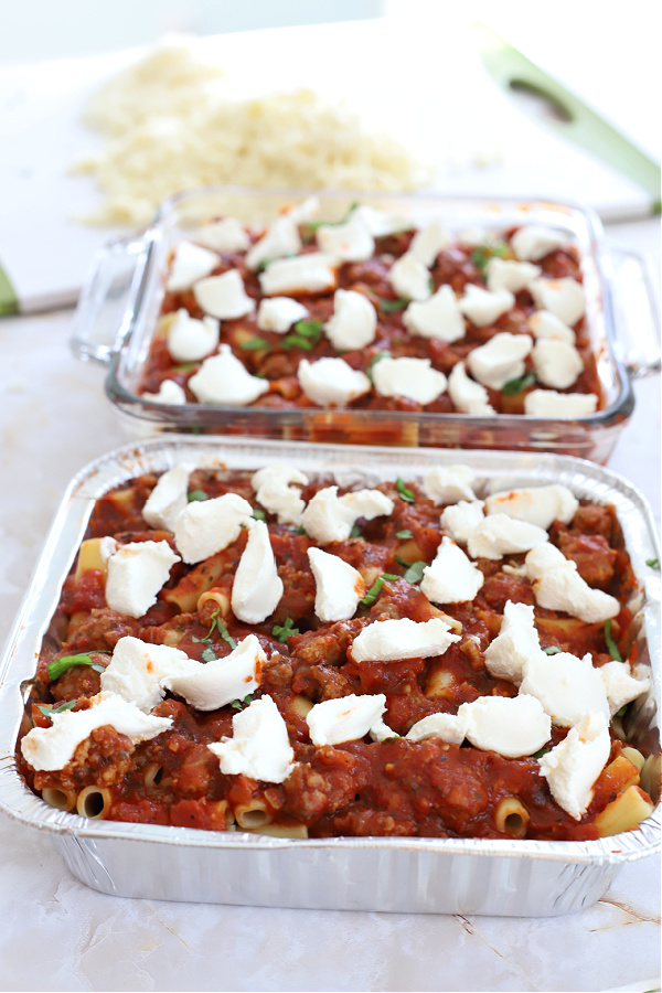 Beginning to layer the sauce, browned Italian sausage, mozzarella, ricotta, Parmesan and pasta for baked ziti casserole.